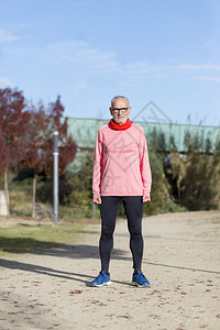 正面全长的玫瑰运动裤赛车手站在公园里锻炼身体退休图片