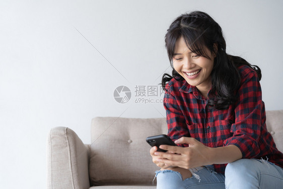 保持身穿红色格衬衫的妇女透过手机看社交媒体着会的一面表情校对PortnoyWorld一种坐着图片