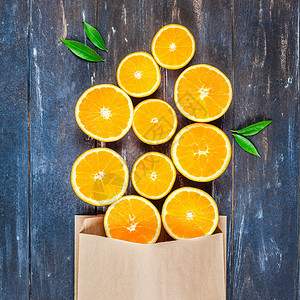 甜的具有创意黑暗风格平板最顶端展示了棕色木制桌背景手工艺购物袋中新鲜橙子水果切片复制空间为供销售或食谱书用的最小夏季鲜柑橘制品或图片