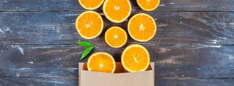 包叶子具有创意的黑暗风格平板最顶端展示了棕色木制桌背景手工艺购物袋中新鲜橙子水果切片复制空间为供销售或食谱书用的最小夏季鲜柑橘制图片