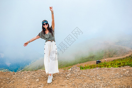 胡托尔雾背景中山美丽快乐的年轻女子美丽的风景雾背中山美丽快乐的年轻女子远足手图片