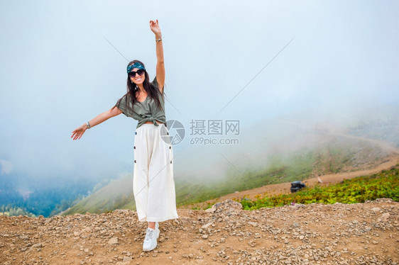 胡托尔雾背景中山美丽快乐的年轻女子美丽的风景雾背中山美丽快乐的年轻女子远足手图片