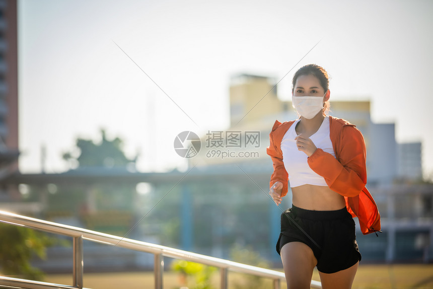 户外戴着口罩跑步的年轻女子图片