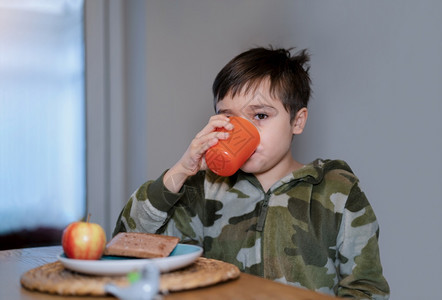 白种人健康的孩子男喝橙汁阅读苹果和巧克力烤面包糕饼孩子上学前在家吃自己做的早饭小朋友孩子们喜悦图片