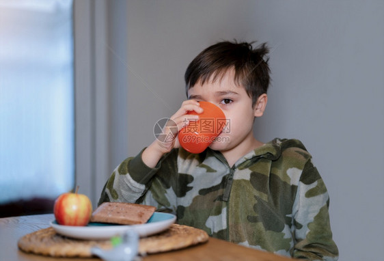 白种人健康的孩子男喝橙汁阅读苹果和巧克力烤面包糕饼孩子上学前在家吃自己做的早饭小朋友孩子们喜悦图片