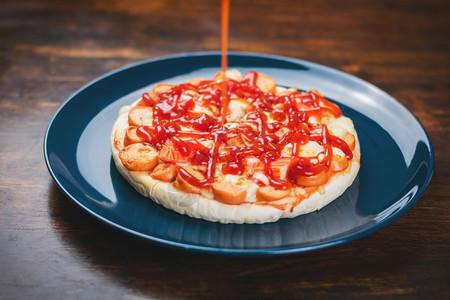 大蒜把番茄酱放在披萨上香肠和螃蟹棒放在木桌的陶瓷板里胡椒意大利背景图片