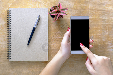 树木在桌上使用黑屏手机的有笔记本和小树放在桌子上多于空白的图片