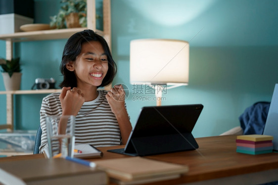放松知识数字的亚洲小女孩成功通过互联网在数字平板电脑上学习同时坐在家中晚上的办公桌旁儿童快乐和笑在家网上学习的概念YTFEntw图片