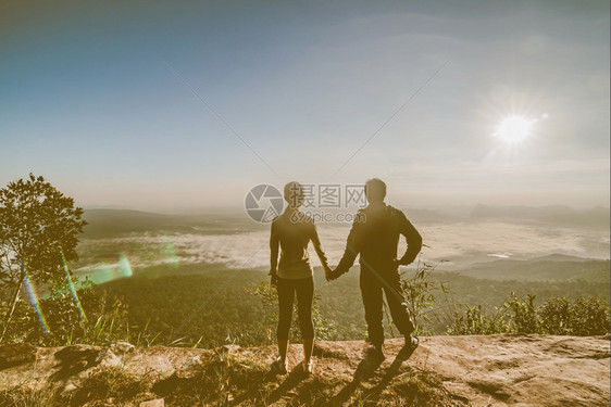 快乐的年轻在山峰露出双臂的一对夫妇徒步旅行者人们图片