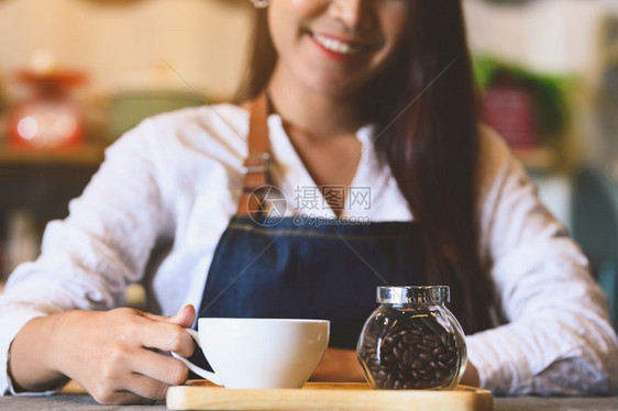 职员女士关闭白咖啡杯为客户提供有美丽的亚洲女律师协会背景的白咖啡杯供职和业服务食品和饮料咖啡店及和餐馆拥有权单位美元咖啡师图片