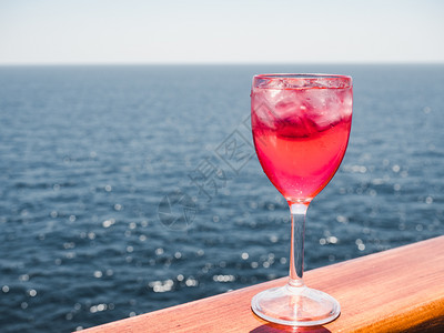 美丽的酒杯有粉红鸡尾酒和冰块在海浪的背景下站在露天的甲板上侧观近距离的休闲概念带着粉红鸡尾酒和冰块旅行马提尼凉爽的甜图片