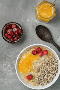 含种子红莓和蜂蜜的燕麦顶视灰色混凝土背景健康食物或饮概念体重控制和健康的生活方式混合薄片超过图片