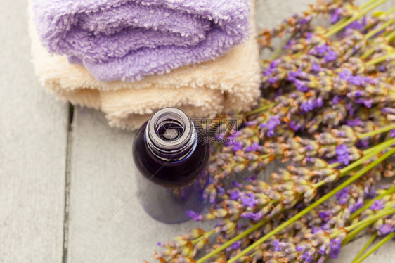 香气毛巾木制桌子上的基本熏衣油和花朵照片图片