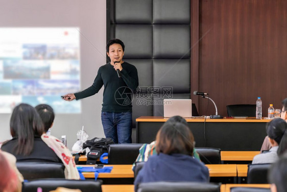 讲台私人的亚洲演讲或在会议室大厅或研讨会议室通过放映屏幕展示舞台时作临穿便装的亚洲演讲人或座以了解观众商业教育和研讨会概念教育家图片