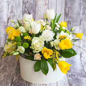 丰富多彩的浪漫灰色盛满美丽花朵包括白面玫瑰圣月和黄色的郁金香花在灰色背景的派普礼品盒中装有绿色叶子的米莫萨花春梅利束华伦人节母亲图片