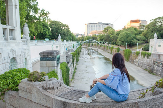 假期年轻有吸引力的户外旅游青年欧洲城市有吸引力的户外旅游青年女对维也纳一条干涸的河流目光回顾在城市中走的维也纳女子肖像旅行图片