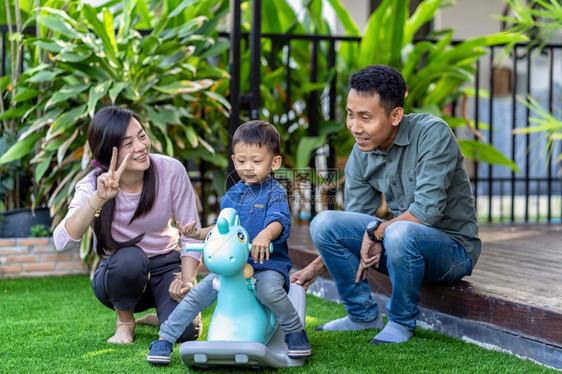 亚洲家庭与儿子一起玩具住在现代学校的前沿草坪供自学或家庭校和单身母亲概念有选择地侧重的家庭和单亲妈概念男生孩子爸图片
