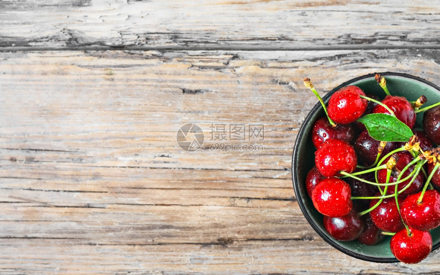 木制的健康新鲜樱桃莓在黑色碗中的滴水放在浅旧的木制板上平布局有复制空间茶点图片