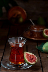 食物红土耳其茶在传统的木头玻璃杯中半个成熟的无花果旁边是背景中的甜点无花果酱老古董木桌近身乡村水果图片