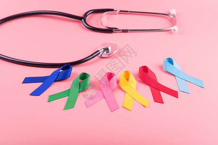 卫生保健听诊器2月4日世界癌症2月4以木制背景为蓝红绿粉色和黄颜的彩带支持人们生活和疾病保健医药概念帮助图片