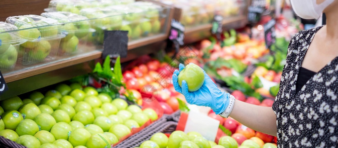 妇女在超市或杂货店内戴硝化手套和持有绿苹果水保护阴冠渗透卫生新正常和19大流行后生活的新健康蔬菜普通的图片