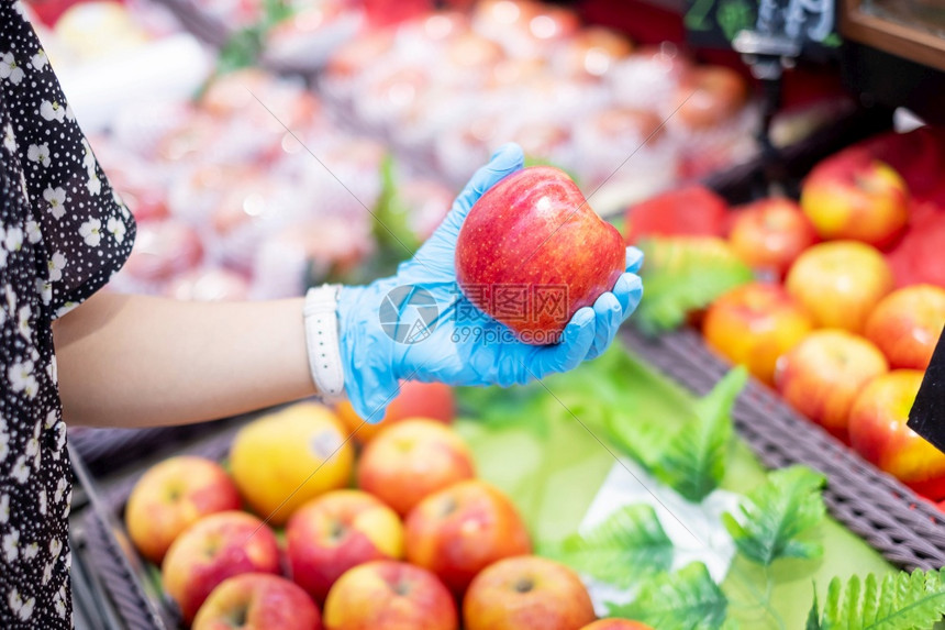 市场妇女在超或杂货店内戴硝化手套和持有红苹果子保护阴冠渗透卫生新正常和19大流行后的生活女士绿色图片