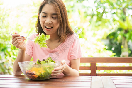 坐在花园旁边房子阳台上吃健康绿色沙拉的保健和营养食品概念她认为在家庭园圃旁边的露台里生活着一个健康的绿色沙拉女蔬菜白种人图片