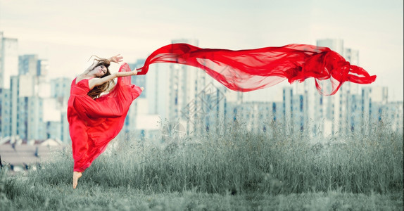 活动芭蕾舞女郎的姿势很美在城市背景中风吹着织物在中飘荡头发体操运动员图片