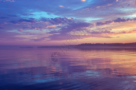 令人惊叹的夜间海景平静的水面反映了色彩多的戏剧天空紫云和雾飘在日落白夜的地平线上这季节是俄罗斯卡雷利亚Karelia俄罗斯Mis图片