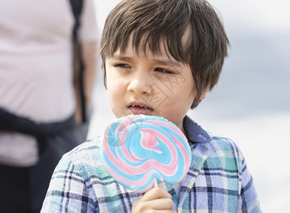 夏天可爱的孩子吃棒糖快乐的小男孩拿着大糖孩子微笑的脸吃甜食活跃的童年在阳光明媚的夏日享受户外游乐晴天请享用图片