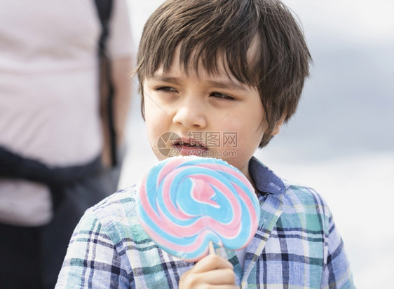 夏天可爱的孩子吃棒糖快乐的小男孩拿着大糖孩子微笑的脸吃甜食活跃的童年在阳光明媚的夏日享受户外游乐晴天请享用图片