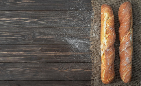 美味的白色面粉冷烘烤包后用白粉制成的法国新鲜袋式面包条位于勃兰布上生锈的深黑木背景小麦香脆的图片
