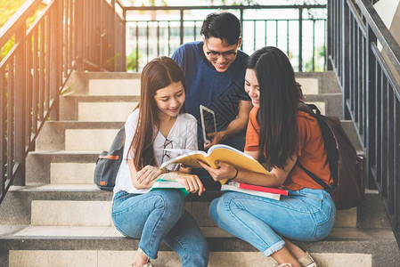 快乐的亚洲大学生一起在楼梯上阅读书籍图片