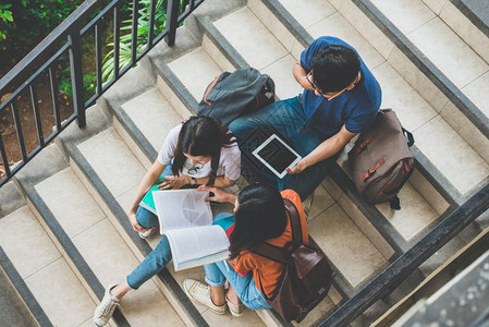 快乐的大学生一起在楼梯上阅读书籍图片