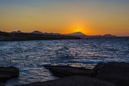 多岩石的希腊米洛斯岛海滩美丽的夕阳日落在希腊米洛斯岛的海滩上基克拉泽斯阳光图片