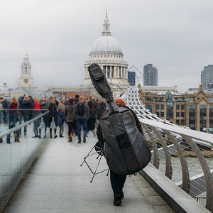 古典无法辨认的音乐街头表演者背着倒置的大提琴在千年桥上俯瞰英国伦敦的圣保罗斯科大教堂可选择的演员图片