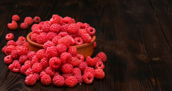 重点猩红黑木桌的粘土碗中草莓有选择焦点有复制空间的成熟草莓近距离为树果汁或甜点设计一个横幅的想法红色图片