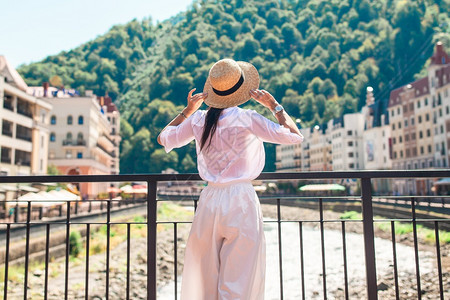 夏天建筑学爬坡道穿着帽子的漂亮女人在山河堤岸上幸福女孩戴着帽子在欧洲城市山河堤岸上一座山河图片