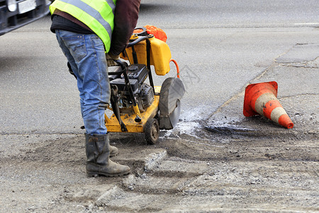 移除道路维修服务一名雇员在修车过程中用汽油雕刻机清除旧沥青修理车辆时用汽油雕刻机拆除旧沥青工人在修建公路期间用汽油切割机下一块坏图片