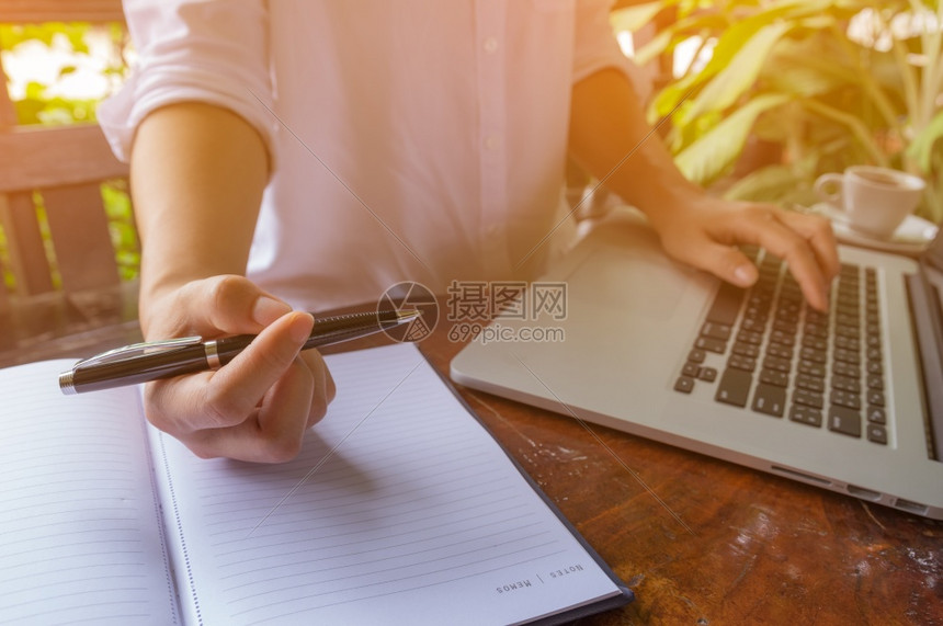 在笔记本上手持自由女信徒手握在咖啡厅的键盘笔记本电脑上女孩使用笔记本电脑打字网上搜索用笔记本电脑浏览软焦点图像木制的咖啡店写作图片