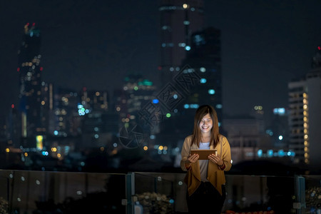 亚洲女商人在泰国Bangkok河边金融区的使用平板牌微笑行动具有职业概念的技术亚洲女商人在泰国Bhangkok河边使用带有微笑的图片