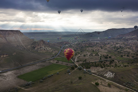 一个五颜六色的气球在黎明时分飞越卡帕多西亚山谷的景色土耳其一个气球在卡帕多西亚的山谷上空飞行天线航班热气球图片