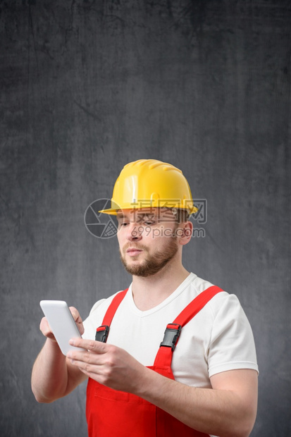 观看应用程序电话一名建筑工人使用智能手机的肖像一名工人使用智能手机的肖像图片