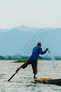 钓鱼茵莱湖的渔夫在一只脚上工作茵莱湖的渔夫在一只脚上工作缅甸划船日落图片