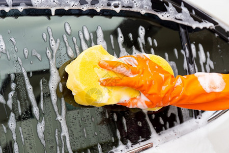 妇女手戴橙色套和黄海绵冲洗侧面的黄色海绵冲洗镜面子现代汽车或清洁洗概念商业辆肮脏的图片