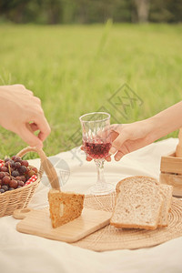 食物草地有人在野餐时给另一个人送杯葡萄汁给另个在野餐中试图拿起面包吃的人吗草图片