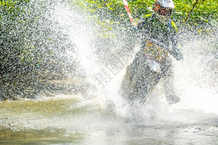 耐力森林中阳光明媚的夏日内地球运动员克服了浅水流大量喷洒着Enduro和大量的水喷雾夏天骑士图片