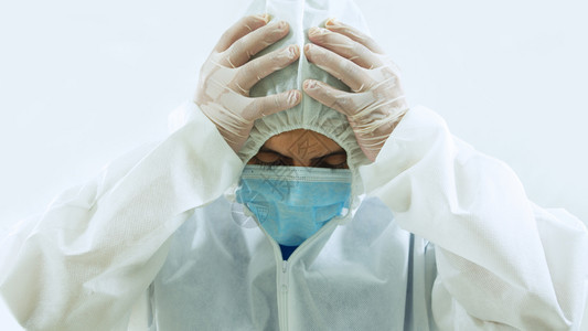 戴蓝色面罩和生物防护服的医正面图双手放在头上以疲倦悲伤哭泣或担心的态度在白色背景上倾斜或担心白色背景拉丁绝望医疗的图片