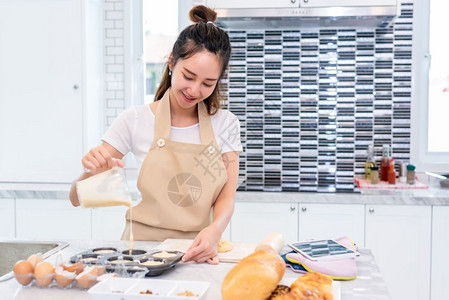 亚洲美女在餐桌上的厨房做饭和烘烤饼干享受节假日与幸福的概念人与生活方式概念家庭与晚宴主题女孩们喜欢用围裙做蛋糕请享用母亲微笑图片