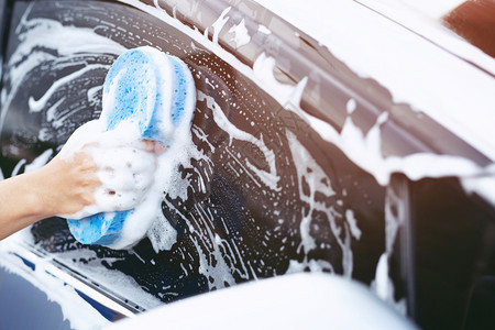 持有手蓝色海绵和泡沫清洗窗的工人男子手持蓝色海绵和泡沫洗涤器衣车人们打蜡图片